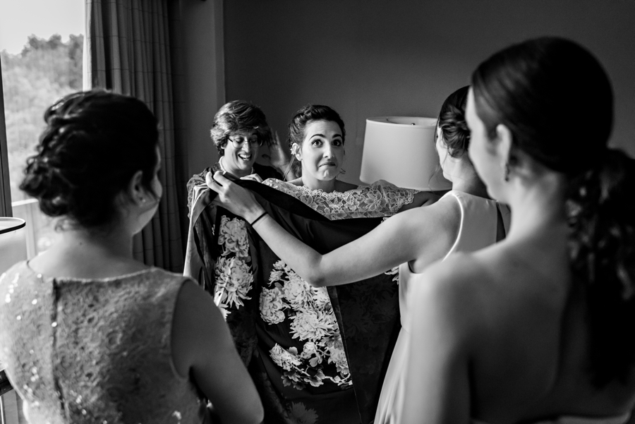 The bridesmaids helping the bride get into her wedding dress.